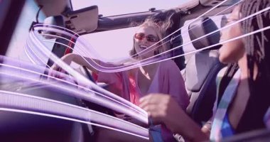 İki arkadaş gülüyor ve üstü açık araba kullanıyor. Işık yolları oluşturuyor. Seyahat havası yaratıyor. Macera, arkadaşlık, eğlence, coşku, yaz, yaşam tarzı, seyahat