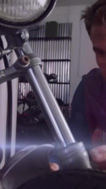 Garajda motorsiklet tamir eden beyaz erkek tamircinin üzerinde parlayan ışıkların animasyonu. Bisiklet haftası konsepti dijital olarak oluşturulmuş video.