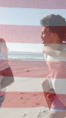 Amerika bayrağının yaz aylarında kumsalda kadınları sırtında taşıyan mutlu erkekler üzerindeki animasyonu. Amerikan vatanseverliği, çeşitlilik ve tatil konsepti dijital olarak oluşturulmuş video.