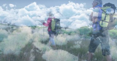 Yürüyüş yapan gezginler bulutlu gökyüzünün altında ceket giyiyorlar. Sırık ve yastıklı çantalar taşıyorlar. Macera, keşif, açık hava, vahşi doğa, manzara, yürüyüş, doğa.