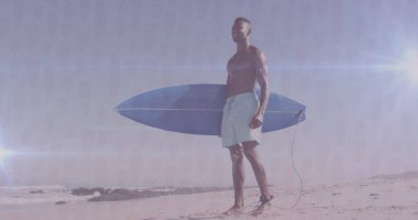 Yüzme şortu giymiş üstsüz bir adam kumlu sahilde dalgalar halinde mavi sörf tahtası tutuyor, lensleri parlıyor. Sahil, deniz kenarı, atletik, tatil, açık hava, coşku, rahatlama
