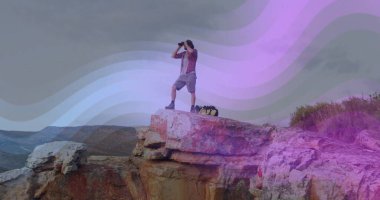 Sırt çantasıyla kumtaşı uçurumunda dikilirken çizme giyen yalnız yürüyüşçüyü taramak. Macera, keşif, engebeli, vahşi doğa, panoramik, yalnızlık, açık hava eğlencesi.