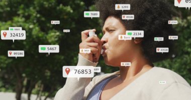 Astım spreyi tutan orta yaşlı bir kadın. Parkta yüzen dijital simgelerle nefes alıyor. Sağlık, teknoloji, doğa, sağlık, açık hava, dijital, canlılık