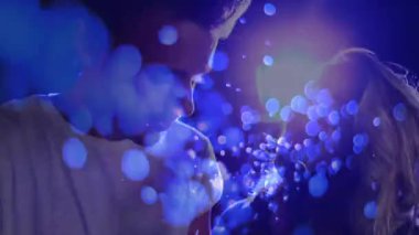 Kadın ve erkek sahneye çıkıyor, mikrofona yaslanıyor, mavi ışıkların altında düet yapıyorlar. Performans, düet, vokalistler, sahne, aydınlatma, atmosfer, bağlantı