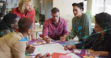 Yeşil kazaklı bir kadın masasında fikir alışverişinde bulunuyor. Fikir akışı çizelgeleri var. İşbirliği, beyin fırtınası, yenilik, takım çalışması, yaratıcılık, analitik, strateji