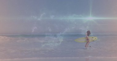 Koşan sörfçü bikinili, sarı sörf tahtasıyla sahilde sığ sörf yapıyor, fotokopi çekiyor. Tatil, yaşam tarzı, minimalizm, macera, açık hava, enerjik, canlı