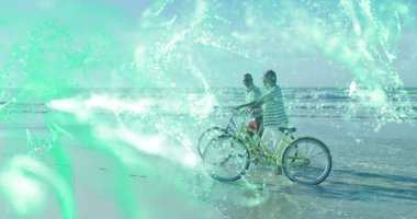 Sahilde denize bakan erkek ve kadın, kruvazör bisikletleri ve yeşil dijital ağ kaplamalı. Macera, sağlık, açık hava, seyahat, teknoloji, boş zaman, manzara