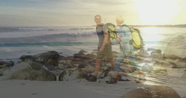 Sırt çantaları ve sırıklar taşıyan yürüyen bir çift kayalık sahil boyunca, altın ışıkta yürüyüş botları giyiyorlar. Macera, keşif, arkadaşlık, doğa, sükunet, açık hava, boş zaman