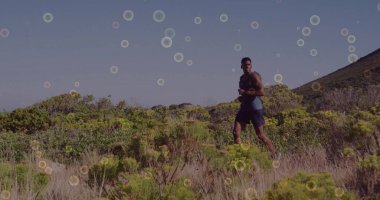 Koşan erkek, çalılık yamaçlarda kolsuz ve koyu şort giyiyor. Kopya uzayı. Atletik, macera, dayanıklılık, fitness, açık hava, hareket, motivasyon