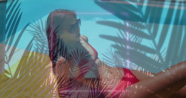 Turkuaz havuz kenarında kırmızı bikini gözlüklü, palmiye gölgelerini gösteren bir Çinli kadın. Tatil, boş zaman, şehir tarzı, açık hava, rahatlama, tropikal, yaz