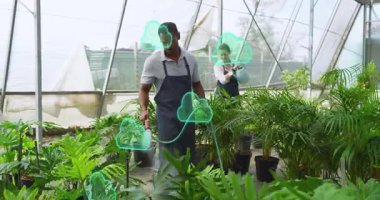 Seradaki bitkileri sulayan iş arkadaşları, veri kaplaması için saksıların etrafında bulut simgeleri oluşturuyorlar. Kentsel tarım, botanik, sürdürülebilirlik, çevre dostu, bahçıvanlık, modern tasarım, çevre