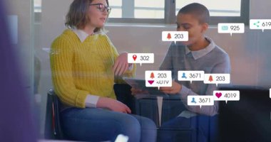 İki meslektaş sosyal medya analisti tableti tıklatıyor ve uyarı simgelerini sel baskınında izliyorlar. İşbirliği, takım çalışması, dijital, teknoloji, ofis, iletişim, ağ