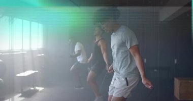 Üç adam bileklerini değiştirirken, atlama halatı egzersizi yapıyor ve çerçevesi arızalı. Fitness, antrenman, takım çalışması, hareket, dijital bozulma, atletik, spor salonu