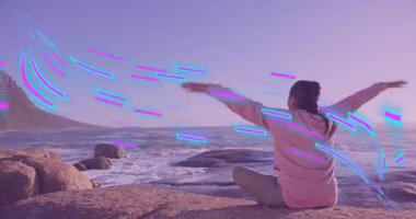 Hintli kadın, meditasyon odağı olmak için yoga kolu akışını şekillendiren neon enerji dalgalarına tepki veriyor. Meditasyon, dinginlik, sahil, sükunet, enerji, farkındalık, pastel
