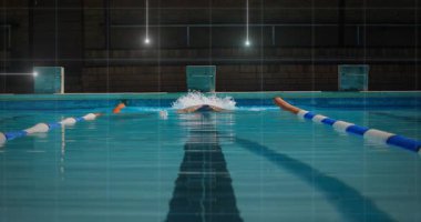 Yüzücü havuz şeridi boyunca süzülüyor, kelebek vuruşunu başlatıyor ve spor eğitimi için su püskürtüyor. Su sporu, su sporu, rekabet, eğitim, atletik, dinamik, su ortamları