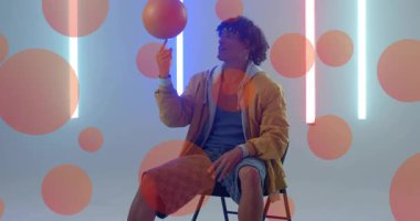 Sporcu parmak üzerinde dönen basketbolu topluyor. Parlayan neon tüplerle, kırmızı daireler çizerek. Sporcu, atletizm, hareket, çağdaş, enerji, gençlik, dinamik