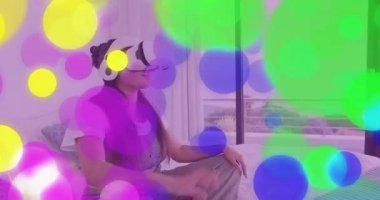 Bağdaş kurmuş, VR kulaklık takan ve dijital teknoloji arayüzünü keşfeden bir kadın. Fütürist, sürükleyici, dijital, yenilik, rahatlama, dinginlik, modern