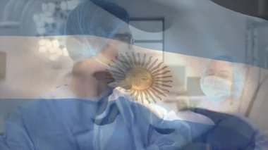 Erkek cerrah asistana doğru dönüyor ve Arjantin bayrağı altında tıbbi aletlere rehberlik ediyor. Tıbbi, sağlık, tıp, profesyonellik, takım çalışması, steril, klinik
