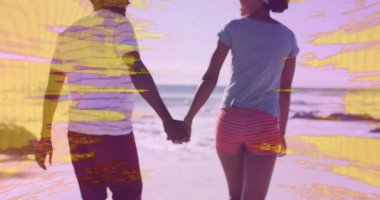 Sahil şeridinde kum ve dalgalarla el ele tutuşan şort ve tişört giyen yürüyen bir çift. Romantik, boş zaman, tatil, yaşam tarzı, deniz kenarı, minimalizm, canlı