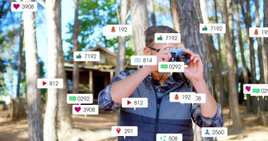 Yorganlı yelek giyen fotoğrafçı, çam ormanları temizliğinde DSLR bilgilendirme simgeleriyle fotoğraf çekiyor. Doğa, açık hava, macera, lens, çerçeve, sükunet, keşif