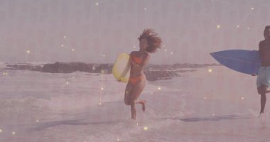 Sahilde kayalık kayalıklarla köpüklü sörf yapan sarı kartonla koşan bir kadın. Tatil, macera, eğlence, yaz, boş zaman, keşif, deniz kenarı