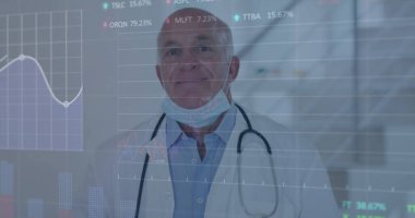 Doktor, klinikteki cam panelin arkasında steteskop cerrahi maskesiyle veri tablolarına bakıyor. Klinik, analitik, tanı, yenilik, profesyonel, sağlık, teknoloji