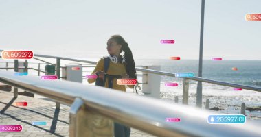 Sarı kazaklı ve sırt çantalı bir kadın gezinti korkuluklarında notlarını gösteriyor. Manzaralı, düşünceli, dijital arayüz, rıhtım, açık hava, sakin, modern