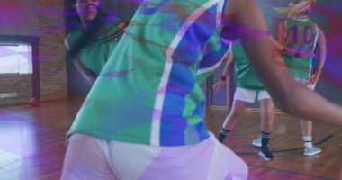 Sporcu defans oyuncularının yanından geçip topu fırlatıyor ve sayı yapmak için kalenin içinden geçiyor. Atletizm, takım çalışması, kararlılık, hareket, rekabet, fitness, spor giyim