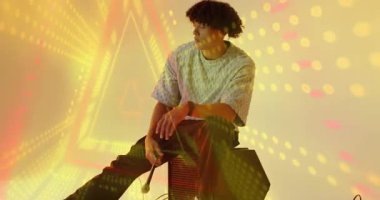 Müzik sanatçısı titreşimli ışıklara tepki veriyor ve sallanan mikrofon kablosunu inceliyor hareket efektlerini yakalıyor. Dinamik, canlı, modern, eğlence, sanatçılık, performans, gösteri