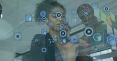 Kadın tasarımcı, takım iş planını gözden geçirirken açık tahta katmanlı haritalar çizmeye başlıyor. İşbirliği, yenilik, dijital grafikler, beyin fırtınası, modern ofis, takım çalışması, stratejik planlama