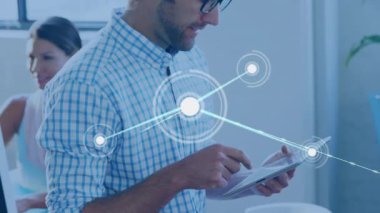 Ofisteki adam, iş arkadaşı gözlemlerken parlayan düğümlerden oluşan veri ağına neden olan tableti tıklatıyor. Teknoloji, işbirliği, yenilik, dijital, iletişim, ağ, geleceksel