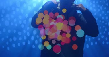 Adam yükselen bokeh ışıklarına tepki veriyor, arkaplandaki ceketi ayarlıyor, dijital teknolojiyi sergiliyor. Soyut, fütüristik, ambient, teknoloji, gece hayatı, canlı, düşünceli