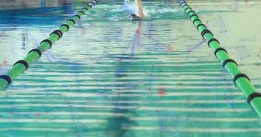 Kadın yüzücü kollarını kaldırarak yüzme antrenmanına başlıyor. Yeşil-siyah şeritli ve felçli. Sporcu, yüzücü, su sporu, antrenman, minimalist, dinamik