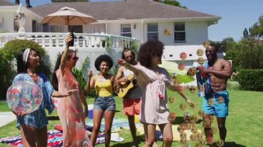 Arkadaslar çimenlik alanda dans ederken akıllı telefon teknoloji emojisini aktifleştiriyor. Kutlama, açık hava, eğlence, canlı, sosyal, yaşam tarzı, gündelik