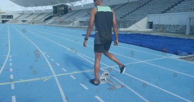 Erkek sporcu ağırlık değiştiriyor ve sprint antrenmanı için mavi pistte başlangıç bloklarına adım atıyor. Sporcu, spor, antrenman, yarışma, hız, performans, açık hava