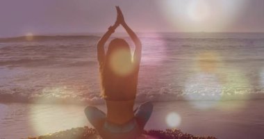 Plajda yoga yapan beyaz bir kadının üzerinde hafif noktaların canlandırılması. Spor, doğa ve dijital arayüz konsepti dijital olarak oluşturulmuş video.