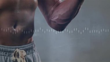 Spor salonunda tişörtsüz bir adam, sağ kolundaki dambıl kıvrımlarını dalga boyu takip istatistikleriyle başlatıyor. Sporcu, güç, fitness, kas, performans, izleme, egzersiz