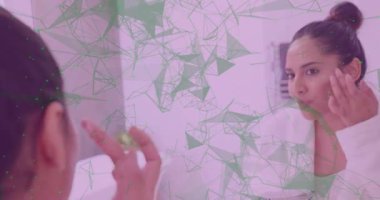 Kadın parmak uçlarını nemlendiriciye daldırıyor ve cildine masaj yapıyor. Yeşil ağ cildini kaplıyor. Cilt bakımı, bencillik, güzellik, sağlık, su, ışıltı, kadın