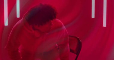 Kırmızı ışıklı stüdyoya kulaklık takmış ve ses teknisyeni demosu sırasında el kol hareketi yapan bir adam giriyor. Stüdyo, ruh hali, sinema, eğlence, minimalizm, rahatlama, teknoloji