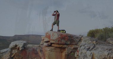 Dürbün ve spor çantasıyla kayalık uçurum kenarından erkek yürüyüşçüyü tarıyorum. Macera, keşif, açık hava, engebeli, manzaralı, vahşi doğa, manzara