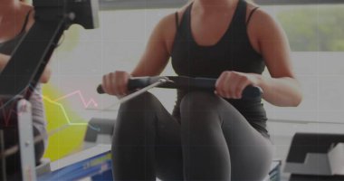 Koyu renk atletizm tişörtlü kürek çeken kadın ve spor salonunda kürek çeken taytlı kadın. Fitness, cardio, wellness, egzersiz, eğitim, motivasyon, güç