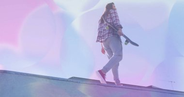 Yürüyen kaykaycı arkada kaykay taşıyor kaykay rampası boyunca, ışık fişekleri, fotokopi alanı. Kentsel, spor, dinamik, canlı, atletik, açık hava, çağdaş