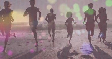 Gün batımında kumlu sahil boyunca mayo giymiş sekiz yetişkinden oluşan bir grup. Okyanus dalgaları yansımaları var. Siluetler, fitness, eğlence, sporcular, manzara, doğa, sükunet