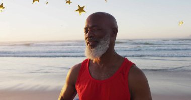 Kumsalda, üzerinde altın yıldız süslemeleri yüzen kırmızı kolsuz, yaşlı bir adam meditasyon yapıyordu. Dinginlik, farkındalık, sağlık, doğa, rahatlama, ruhsal, gençleşme