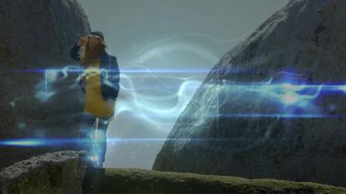 Bir kadın kadraja giriyor ve teknolojide çıkıntıyı geçerken mavi-beyaz kıvılcım saçıyor. Macera, keşif, dijital, manzara, dinamik, açık hava, modern