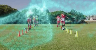 İki futbolcu slalom külahları sallıyor ve turkuaz kıvrımlı top fırlatıyorlar. Sporcular, spor, çeviklik, takım çalışması, eğitim, açık hava, dinamik