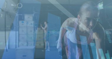 Dambılları kaldıran kadın spor salonunda eğilmiş, kondisyon kutuları ve çizelgelerle oynuyordu. Güç, eğitim, performans, analiz, fitness, sağlık, dinamik