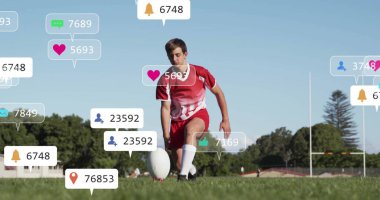 Kırmızı üniformalı, oval topu kale direğinin bildirim simgeleriyle saha tişörtüne koyan diz çökmüş bir atlet. Sporcu, spor, aktivite, açık hava, rekabet, fitness, takım çalışması