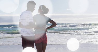 Bellerini kucaklayan, kıyı şeridinde parlak gökyüzünün altında durgun denize bakan Afrika kökenli Amerikalı çift. Romantik, huzur, rahatlık, açık hava, canlı, uyum, doğal