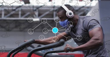 Merdiven tırmanan, gri tişört giyen mavi maskeli ve kulaklıklı bir adam. Fitness, egzersiz, teknoloji, sağlık, güç, eğitim, yenilik